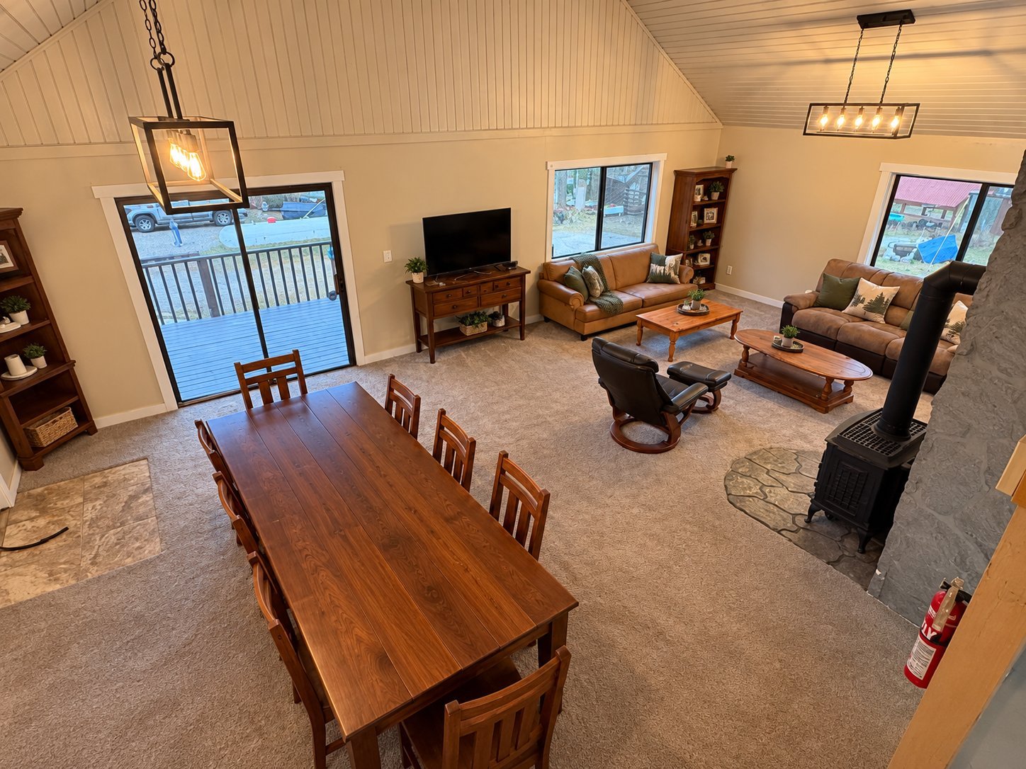 Spacious open-concept living room with dining table, furniture, TV, and large windows overlooking snowy landscape
